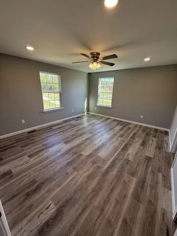 an empty room with windows and ceiling fan
