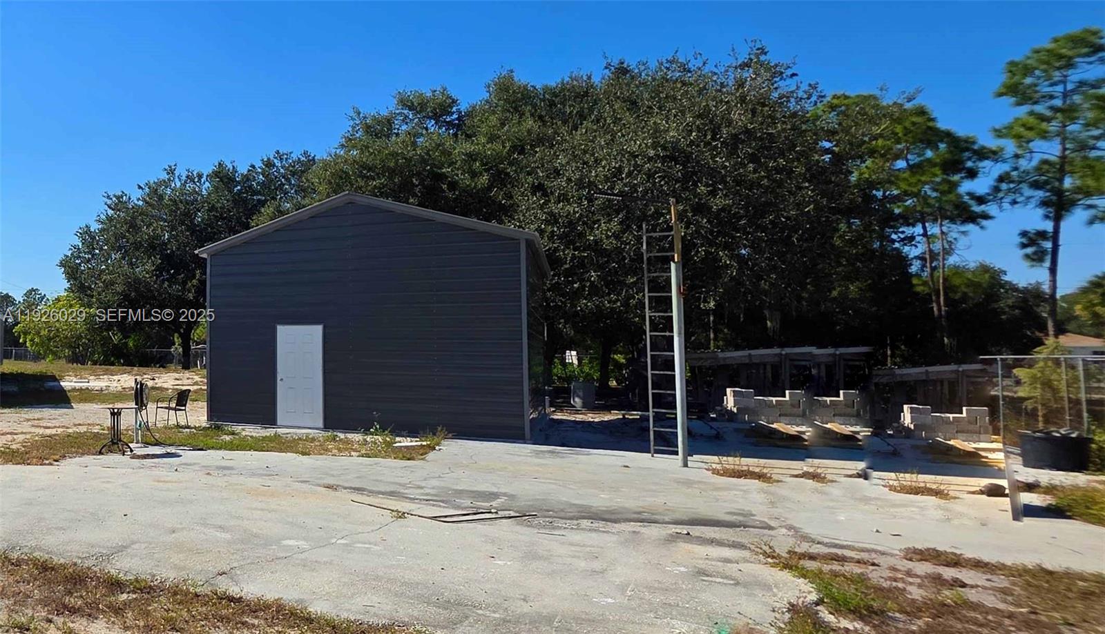 527 Perimeter Road Clewiston, FL 33440 - Photo 25 of 40 a backyard of a house with table and chairs under an umbrella