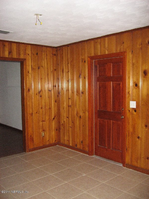 6732 Heidi Road Jacksonville, FL 32277 - Photo 4 of 10 an empty room with wooden walls