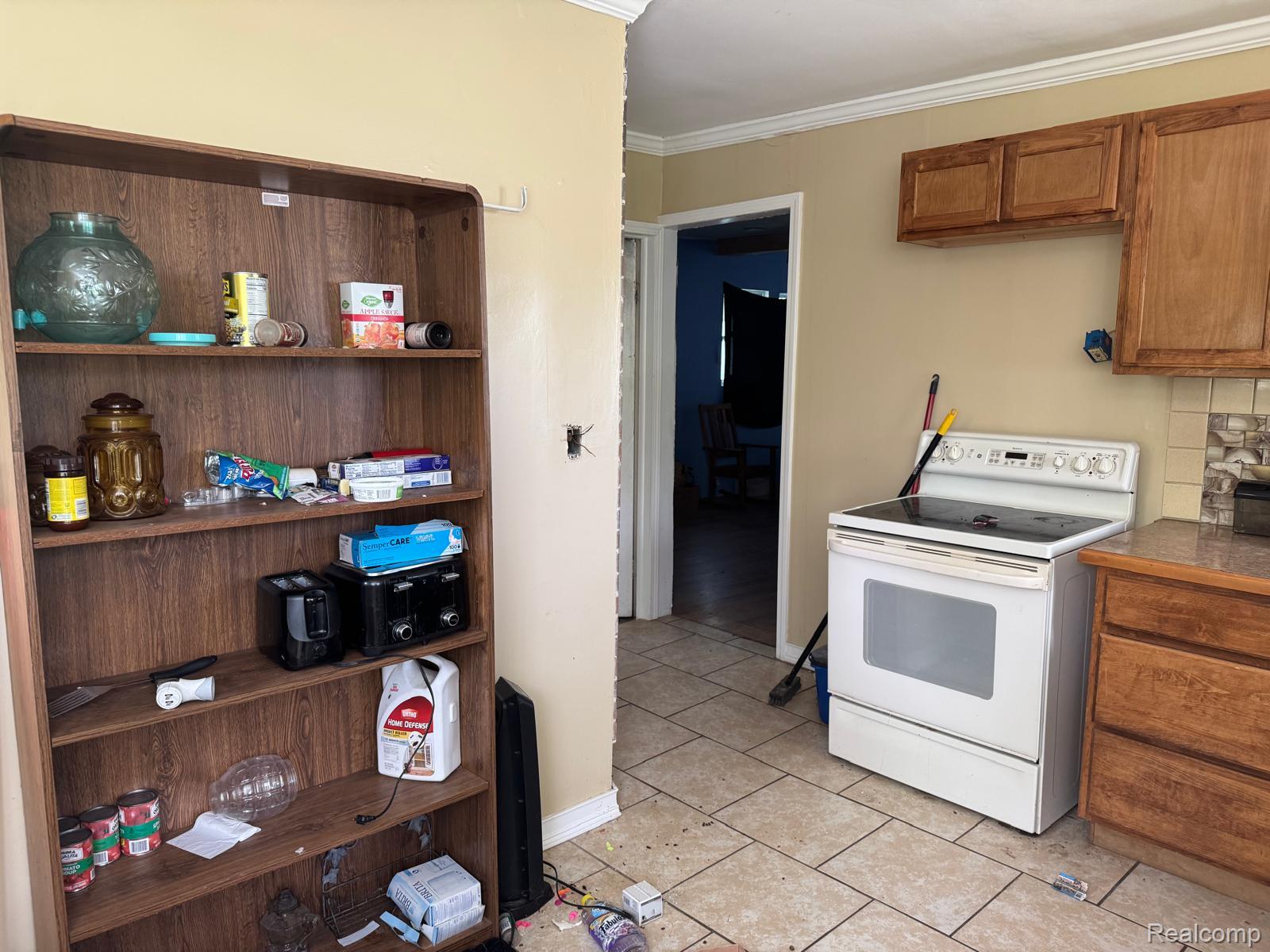 1610 Kent Street Flint, MI 48503 - Photo 6 of 11 Kitchen with white range with electric cooktop, wood finish cabinets, light tile patterned floors, and crown molding