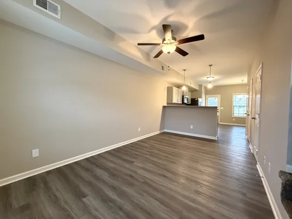 an empty room with wooden floor ceiling fan and windows