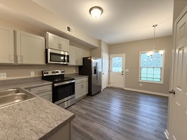 a kitchen with granite countertop a stove top oven a sink dishwasher a refrigerator and cabinets with wooden floor