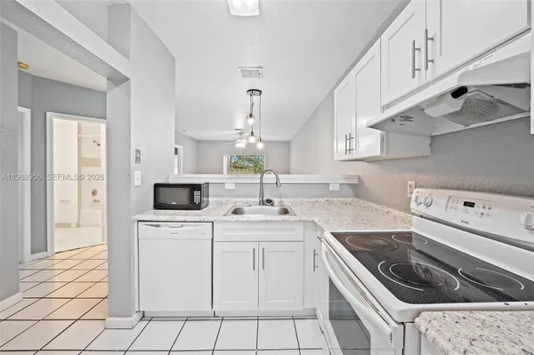 a kitchen with white cabinets appliances and sink
