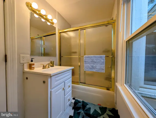 a bathroom with a sink and mirror with bathtub