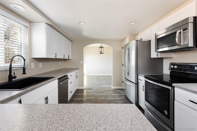 a kitchen with stainless steel appliances granite countertop a stove a sink and a microwave