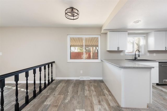 a view of kitchen with a sink wooden cabinets and window