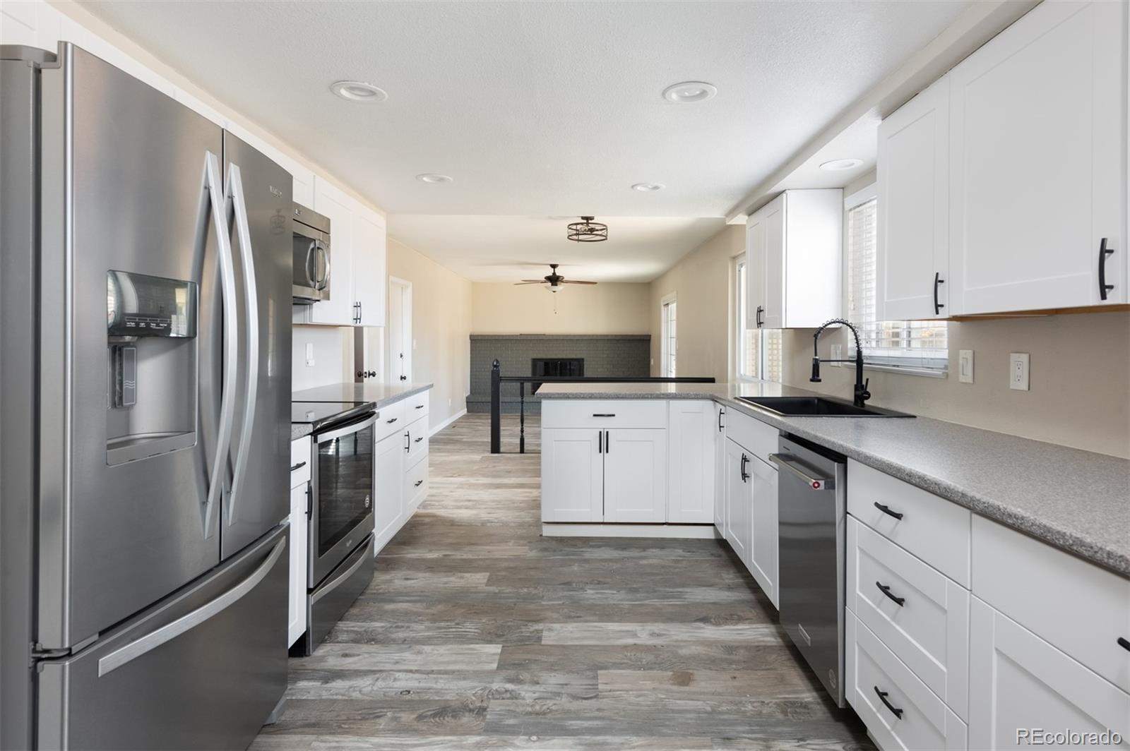 13766 Omega Circle Lone Tree, CO 80124 - Photo 10 of 37 a kitchen with stainless steel appliances kitchen island granite countertop a refrigerator a sink a stove and white cabinets