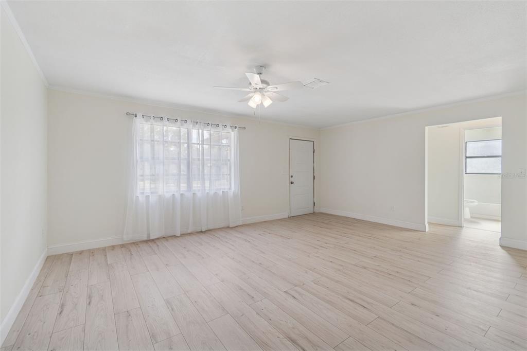 7337 Cambridge Way Clearwater, FL 33764 - Photo 5 of 28 an empty room with wooden floor ceiling fan and windows