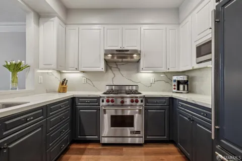 a kitchen with stainless steel appliances granite countertop a stove and white cabinets