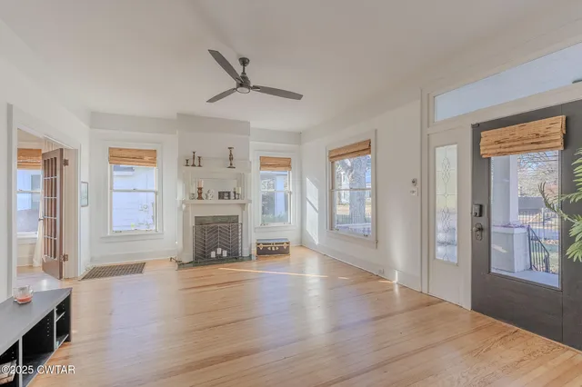 a view of a livingroom with wooden floor a ceiling fan and windows