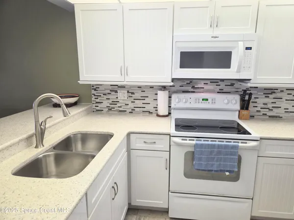 a kitchen with granite countertop white cabinets and white appliances