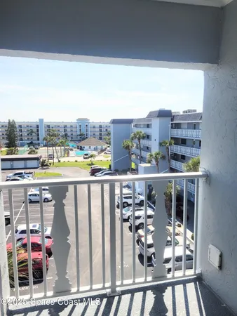 a balcony view with a couple of cars parked in front of it