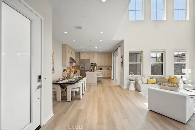 a living room with stainless steel appliances furniture a rug kitchen view and a large mirror