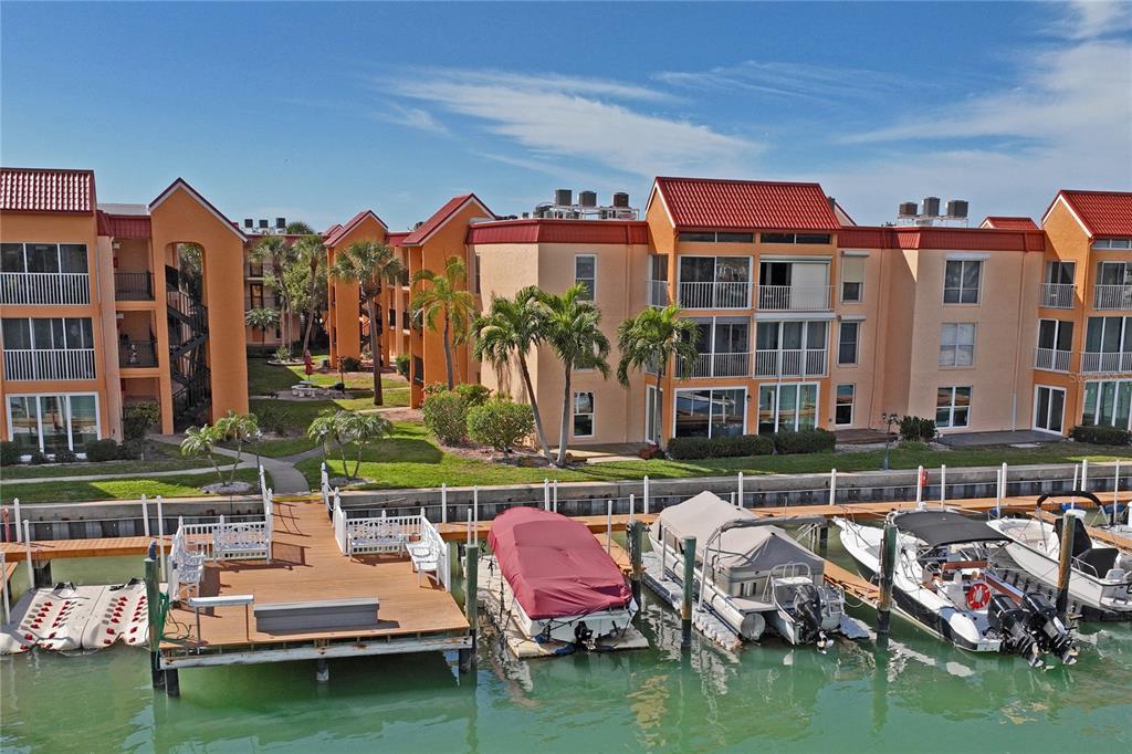 8931 Blind Pass Road, Unit 355 St. Pete Beach, FL 33706 - Photo 1 of 1 a view of a building with floor to ceiling windows yard and a table and chairs