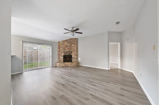 a view of empty room with wooden floor and fireplace