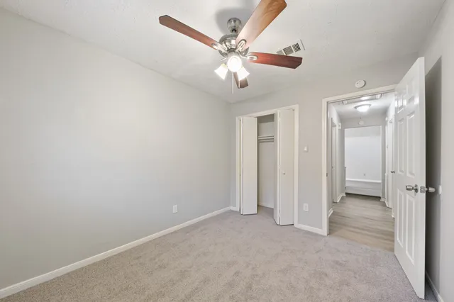an empty room with closet and a ceiling fan