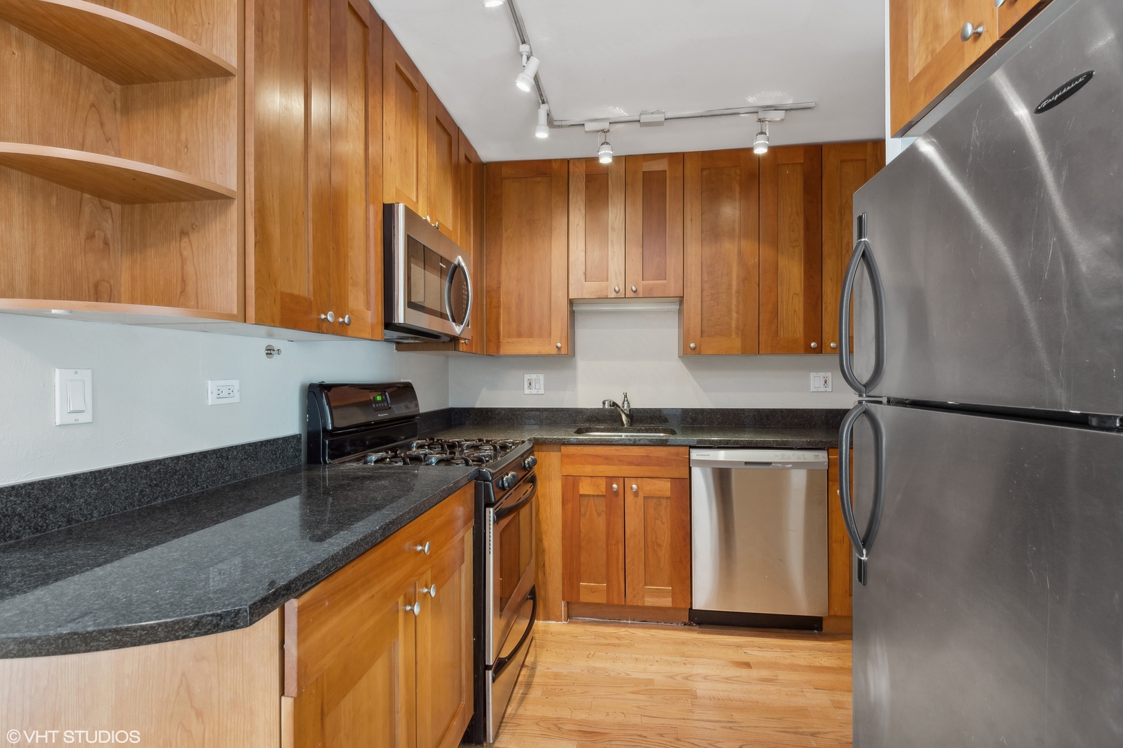 4144 North Sheridan Road, Unit 205 Chicago, IL 60613 - Photo 10 of 18 a kitchen with stainless steel appliances granite countertop a refrigerator a stove and a sink with wooden floor