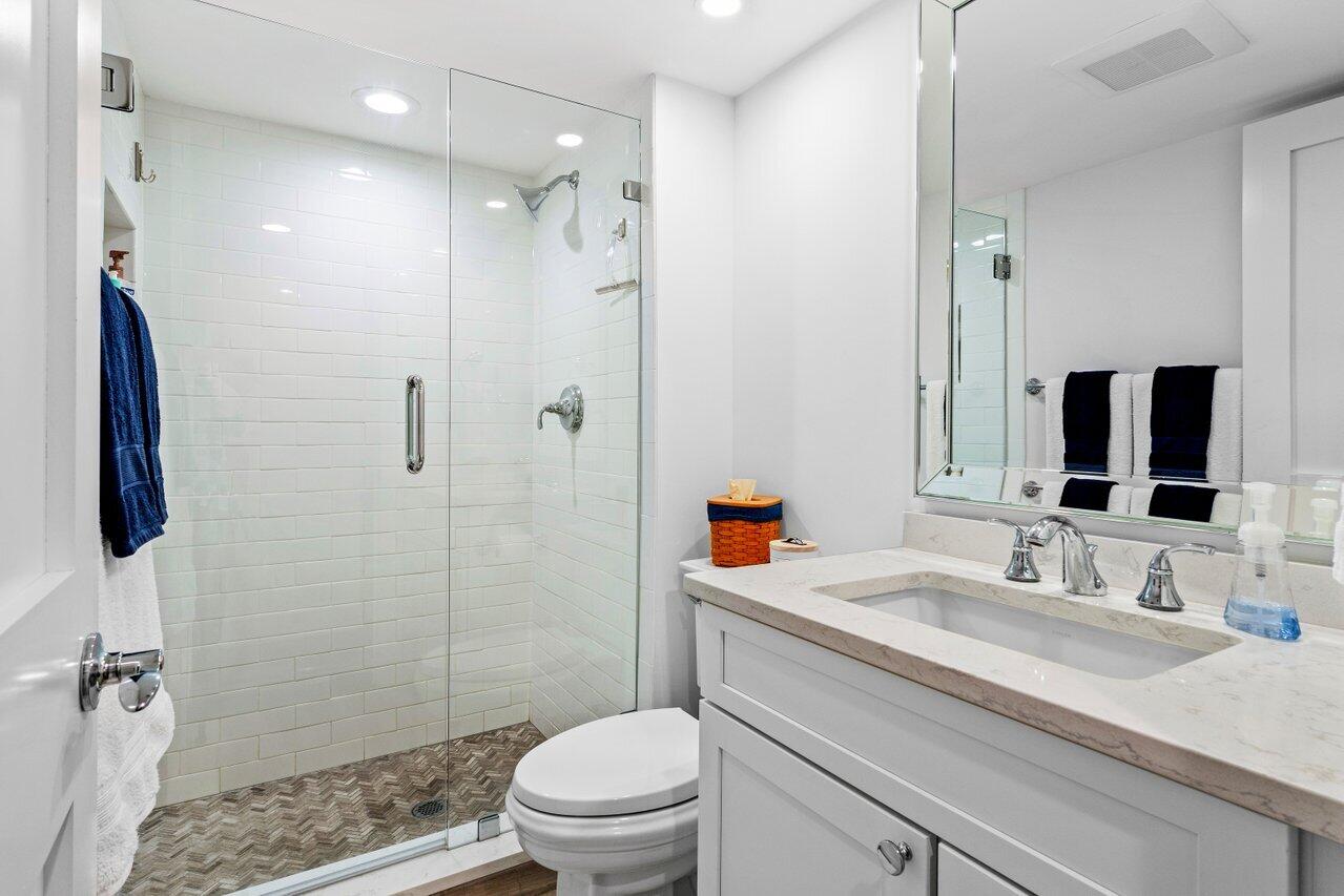 176 Helios Drive, Unit 104 Jupiter, FL 33477 - Photo 14 of 59 a bathroom with a granite countertop sink a mirror a toilet and shower