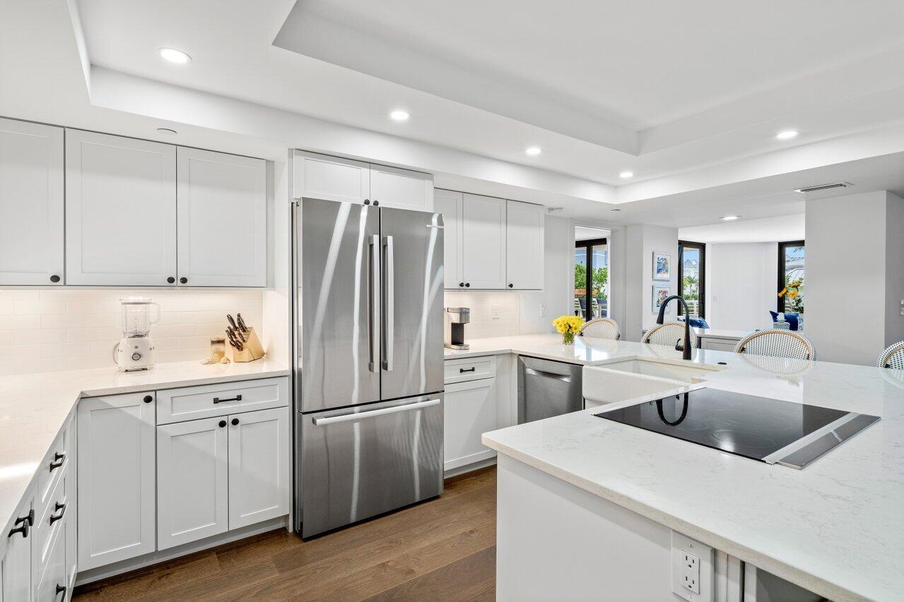 176 Helios Drive, Unit 104 Jupiter, FL 33477 - Photo 30 of 59 a kitchen with a sink a refrigerator and white cabinets
