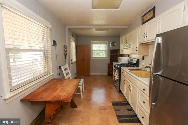 a kitchen with stainless steel appliances granite countertop a refrigerator a sink dishwasher a stove and white countertops with wooden floor