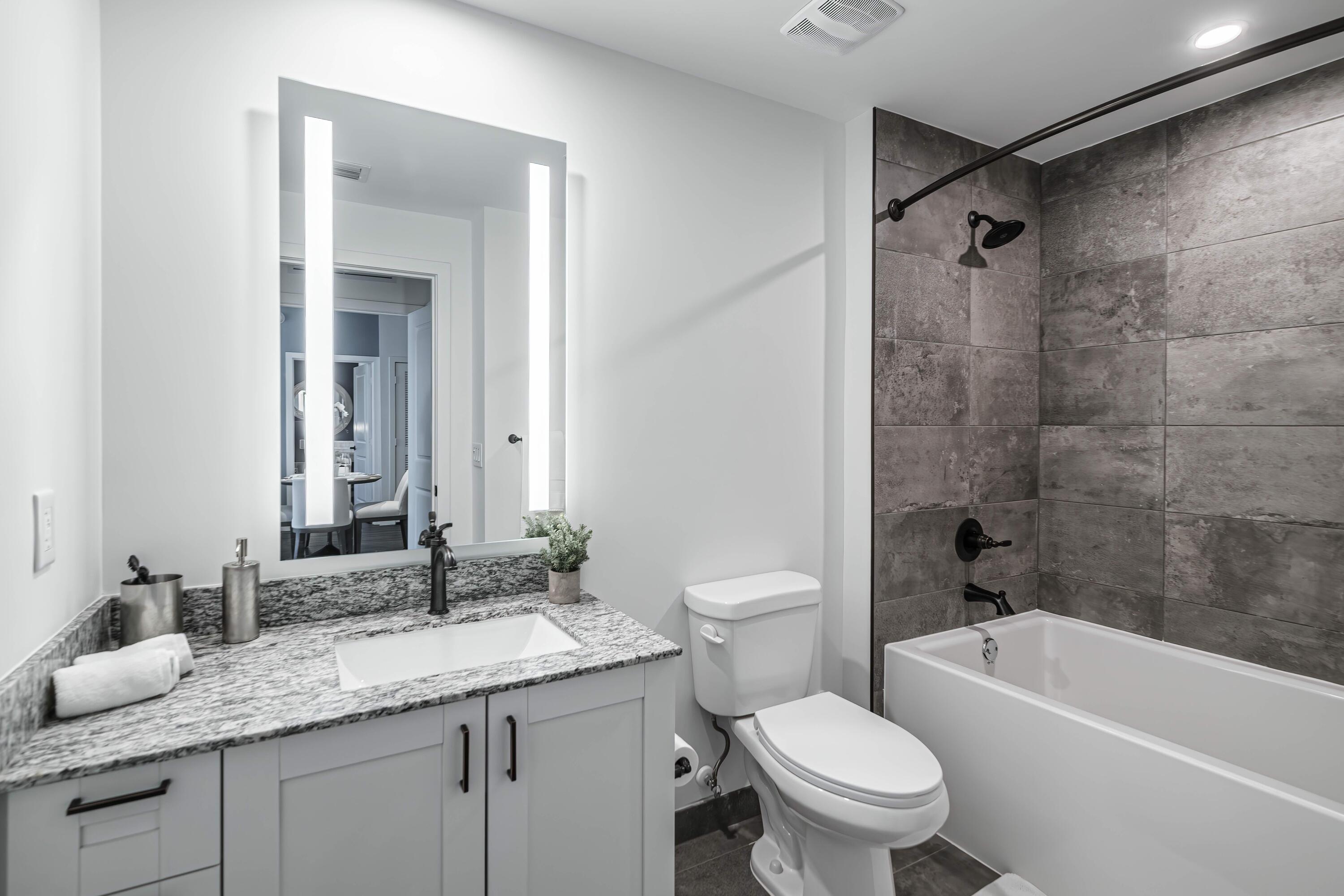 2000 Stirling Road, Unit 14103 Hollywood, FL 33020 - Photo 20 of 35 a bathroom with a granite countertop sink a toilet a mirror a bathtub and shower