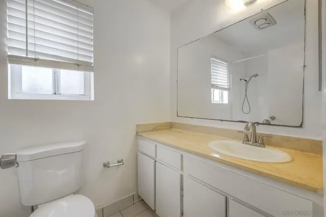 a bathroom with a granite countertop sink toilet and a mirror