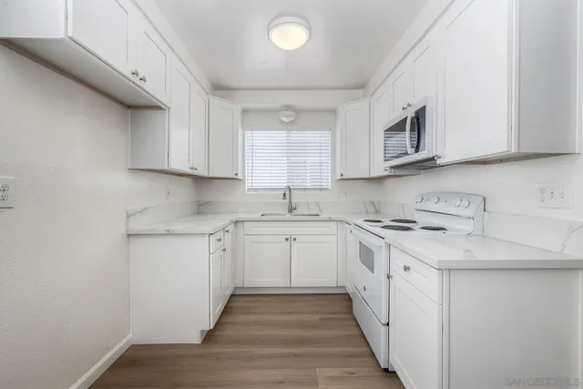 a kitchen with granite countertop cabinets stainless steel appliances a sink and a window