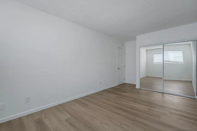 a view of an empty room with wooden floor and windows