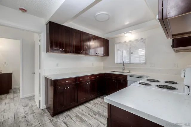 a kitchen with a sink and a stove top oven with wooden floor