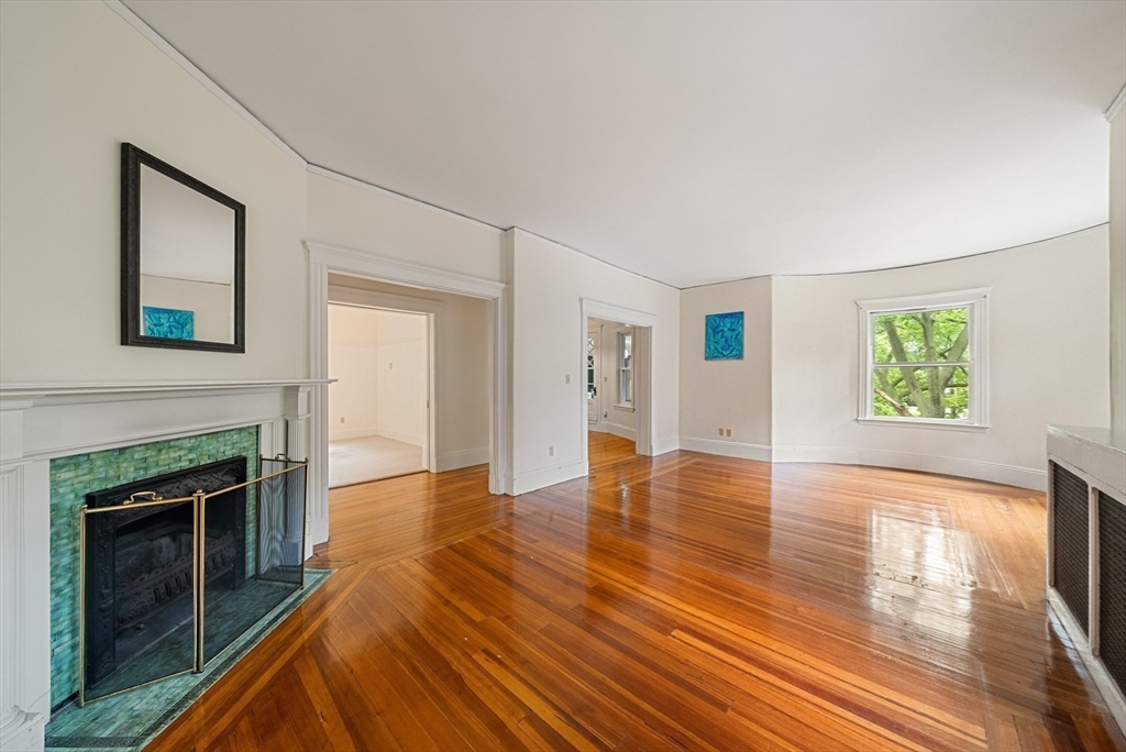 179 Rawson Road, Unit 2 Brookline, MA 02445 - Photo 3 of 42 an empty room with wooden floor a fireplace and windows