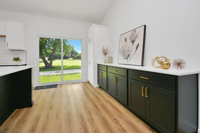 a kitchen with a sink appliances cabinets and a large window