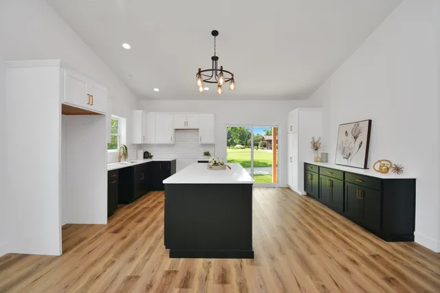 a large kitchen with stainless steel appliances a large counter top a wooden floor a window and a sink