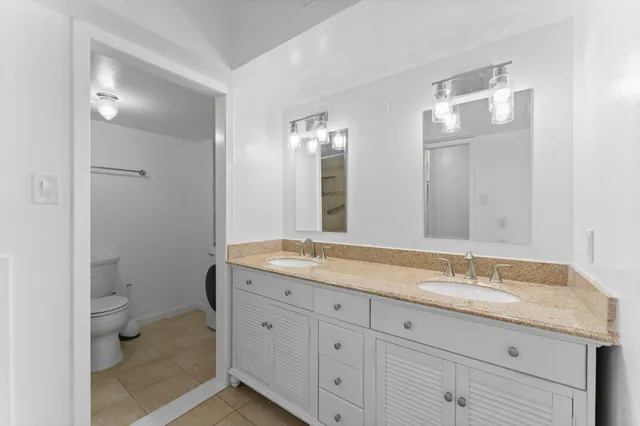 a bathroom with a granite countertop sink a toilet and a mirror