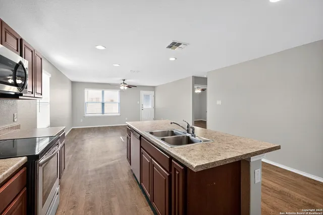 a kitchen with granite countertop kitchen island a sink stove and wooden floor