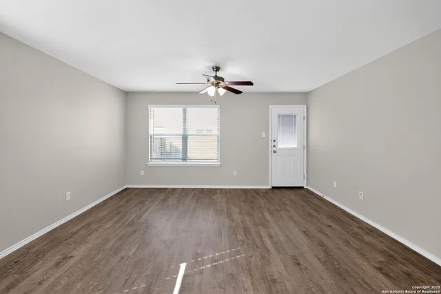 an empty room with wooden floor and windows