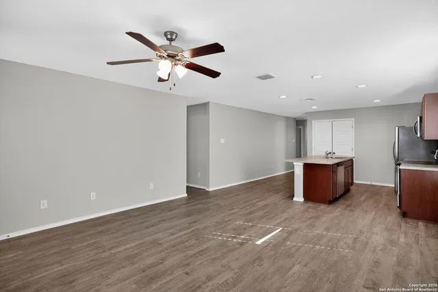 a view of a livingroom with a ceiling fan & wooden floor