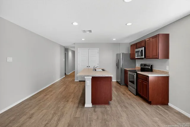 a kitchen with stainless steel appliances granite countertop a stove a sink dishwasher and a refrigerator with wooden floor