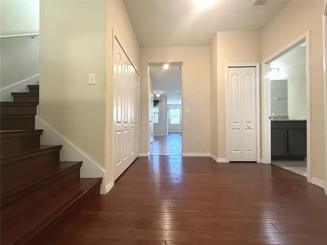 a view of an empty room with wooden floor and stairs