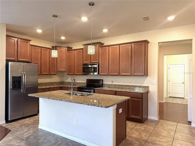 a kitchen with kitchen island granite countertop a sink counter top space cabinets and stainless steel appliances