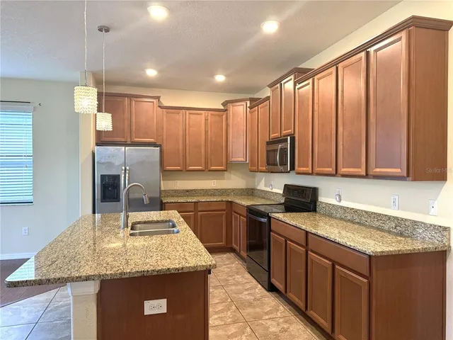 a kitchen with stainless steel appliances granite countertop a sink counter space cabinets and a large window