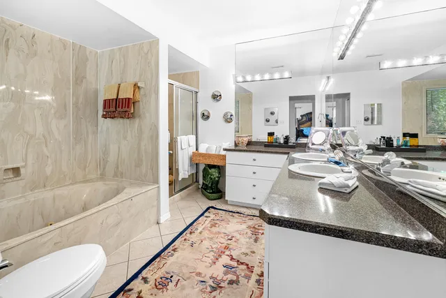 a bathroom with a granite countertop sink mirror bathtub and toilet
