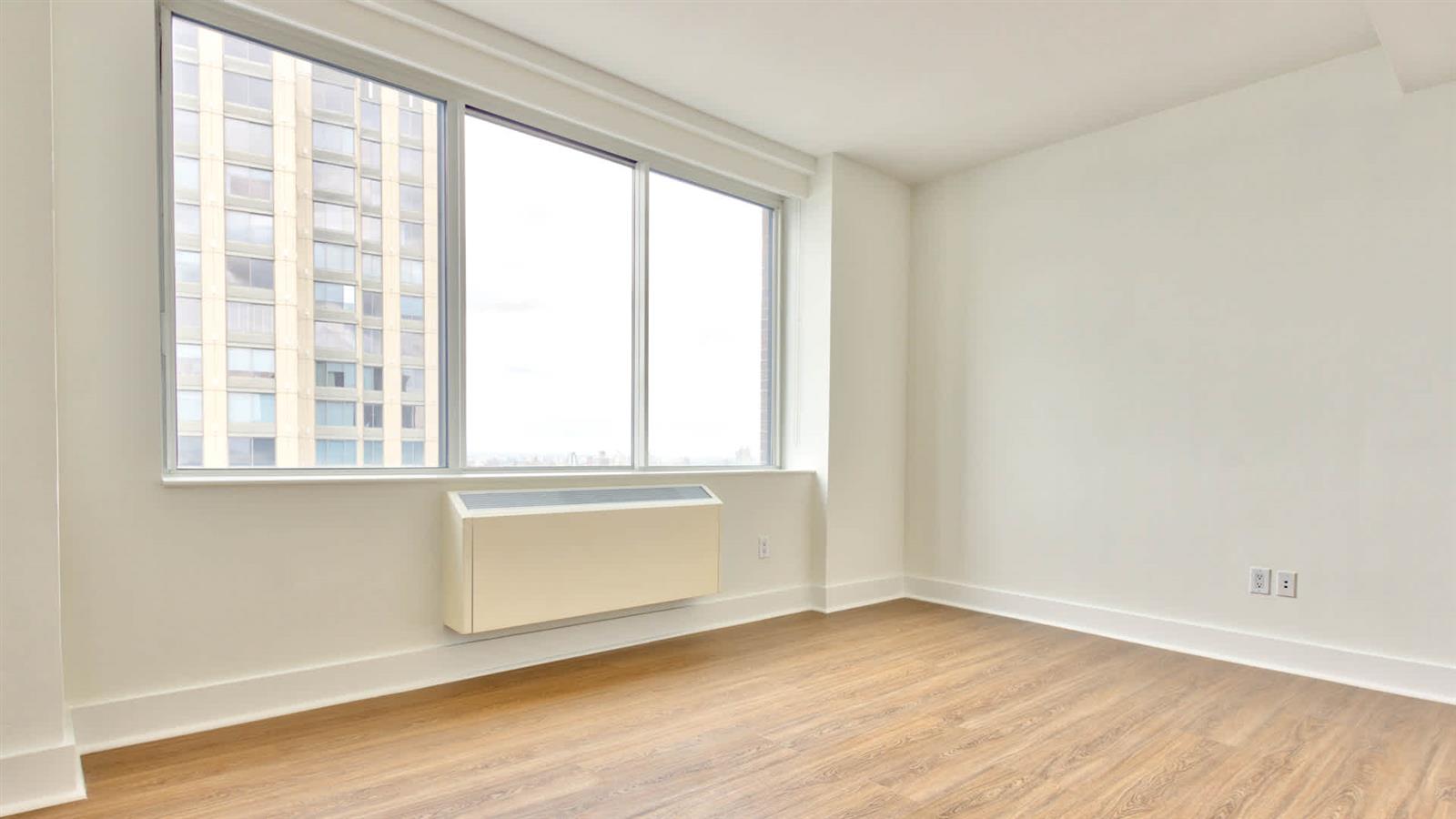 180 Riverside Boulevard, Unit 6V Manhattan, NY 10069 - Photo 5 of 10 a view of an empty room with wooden floor and a window
