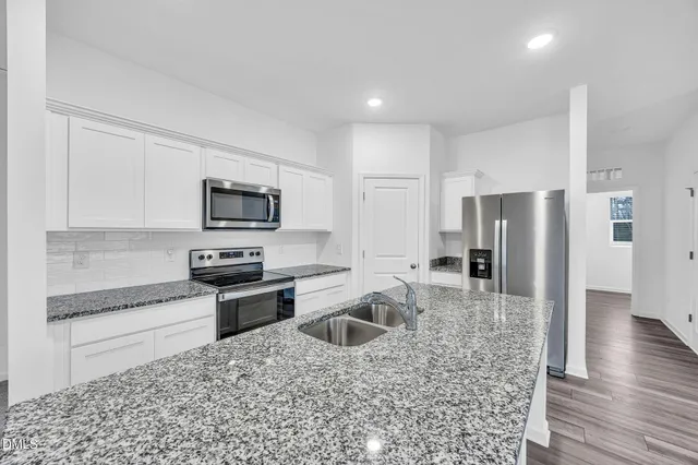 a kitchen with stainless steel appliances granite countertop a refrigerator a stove a sink and a microwave