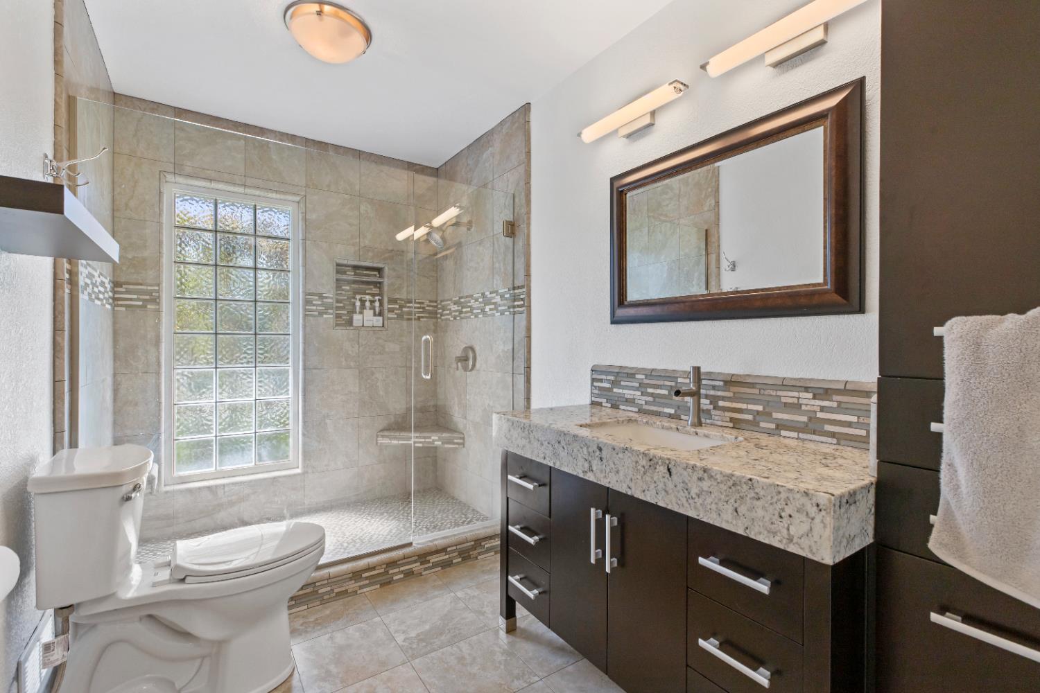 908 Newcastle Court Modesto, CA 95355 - Photo 12 of 25 a bathroom with a granite countertop sink toilet and shower