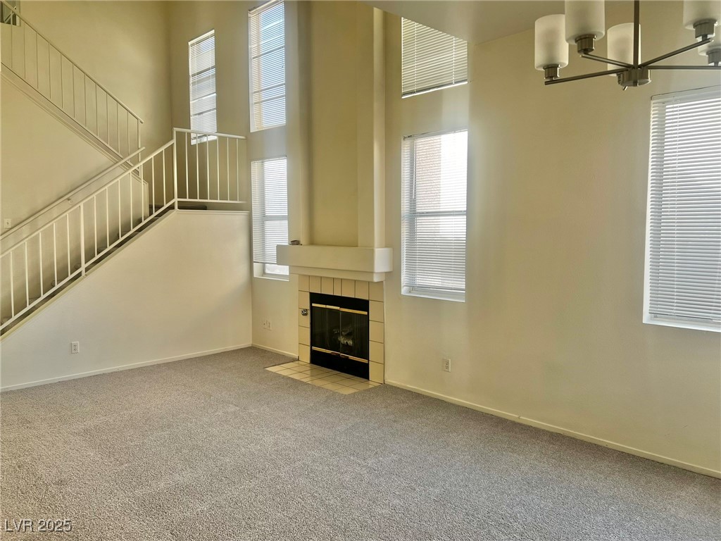 6656 Goldencreek Way, Unit HOME Las Vegas, NV 89108 - Photo 4 of 22 Unfurnished living room with a high ceiling, carpet floors, a tiled fireplace, and a chandelier