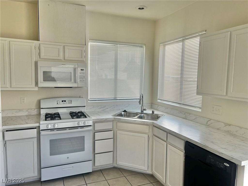 6656 Goldencreek Way, Unit HOME Las Vegas, NV 89108 - Photo 6 of 22 Kitchen featuring white appliances, white cabinets, light countertops, and light tile patterned floors