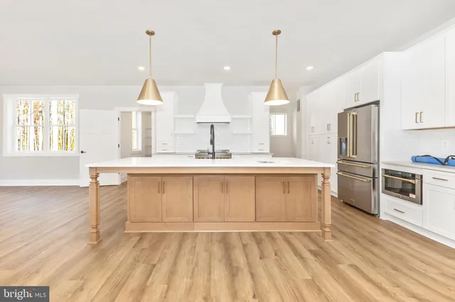 a large kitchen with kitchen island a sink a stove and a refrigerator