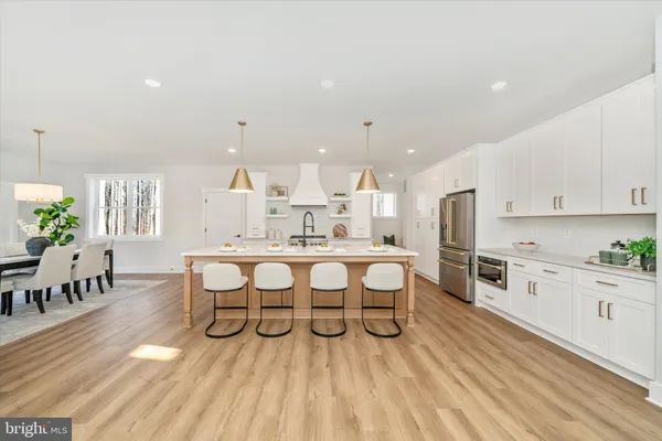 a kitchen with stainless steel appliances granite countertop a table chairs in it and white cabinets