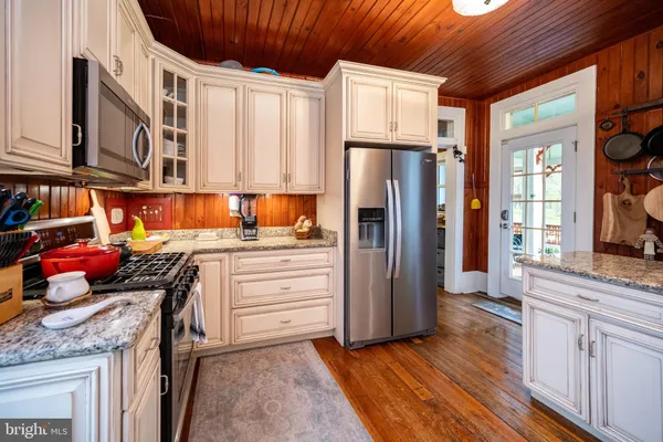 a kitchen with granite countertop white cabinets and white appliances