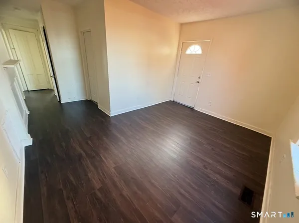 an empty room with wooden floor and mirror